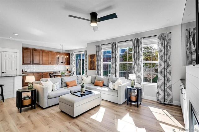 living room featuring ceiling fan with notable chandelier and light hardwood / wood-style floors