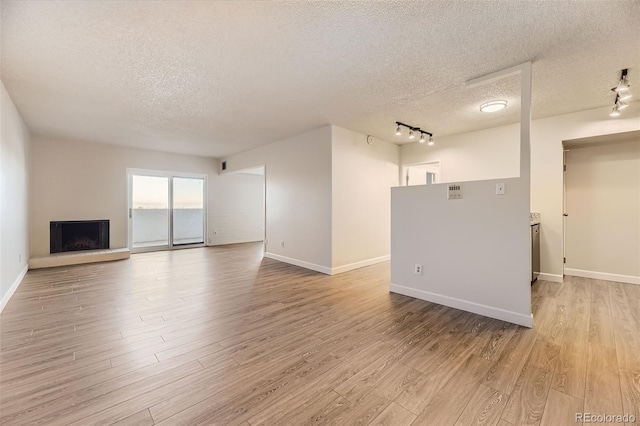 unfurnished living room featuring light hardwood / wood-style floors, a textured ceiling, and track lighting