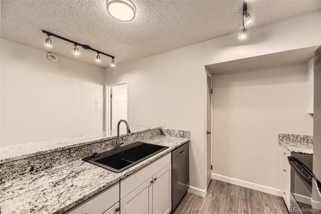 kitchen with light stone countertops, sink, stainless steel dishwasher, and a textured ceiling