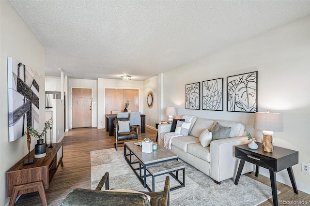 living room featuring a textured ceiling, wood finished floors, and baseboards