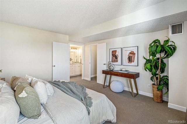 bedroom with baseboards, visible vents, ensuite bathroom, a textured ceiling, and carpet flooring