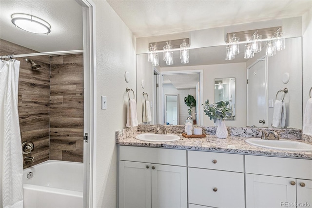 bathroom featuring double vanity, a textured ceiling, shower / bath combo with shower curtain, and a sink