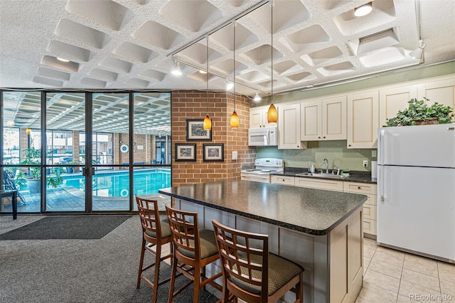 kitchen with a breakfast bar area, white appliances, a sink, a wall of windows, and dark countertops