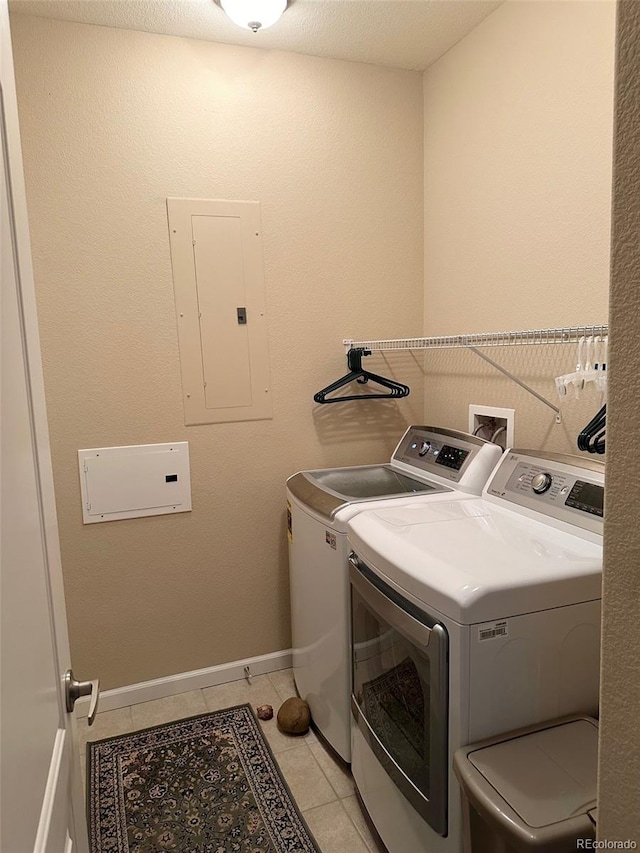 clothes washing area featuring electric panel, light tile patterned flooring, washer and dryer, and a textured ceiling