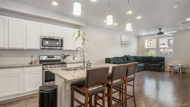 16231 E Warner Pl, Denver, CO 80239 - kitchen featuring stainless steel appliances, backsplash, open floor plan, ceiling fan, and dark wood-style flooring