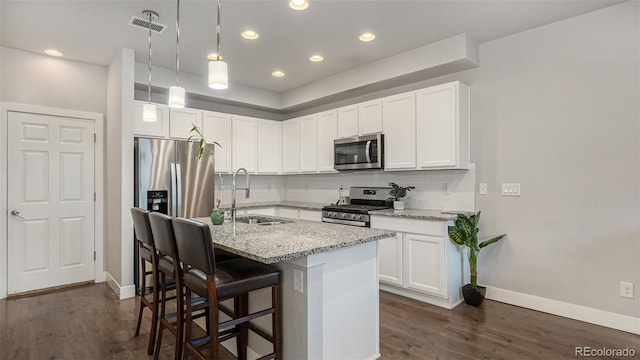 16231 E Warner Pl, Denver, CO 80239 - kitchen with stainless steel appliances, tasteful backsplash, light stone counters, dark wood finished floors, and a kitchen breakfast bar