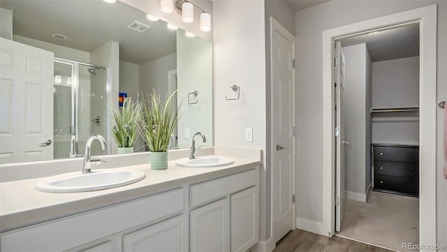 bathroom featuring hardwood / wood-style flooring, vanity, and a shower with shower door