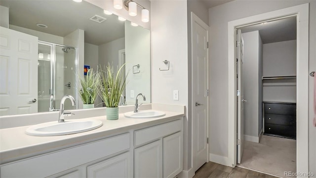 16231 E Warner Pl, Denver, CO 80239 - bathroom featuring double vanity, a shower stall, a closet, and wood finished floors