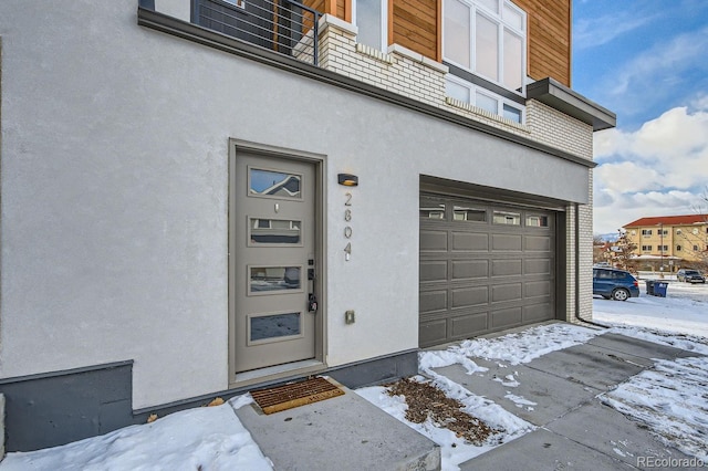 snow covered property entrance featuring a garage