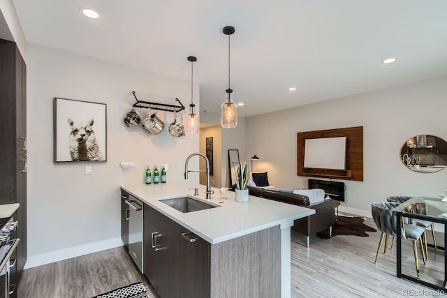 kitchen with pendant lighting, sink, stainless steel dishwasher, kitchen peninsula, and light hardwood / wood-style flooring