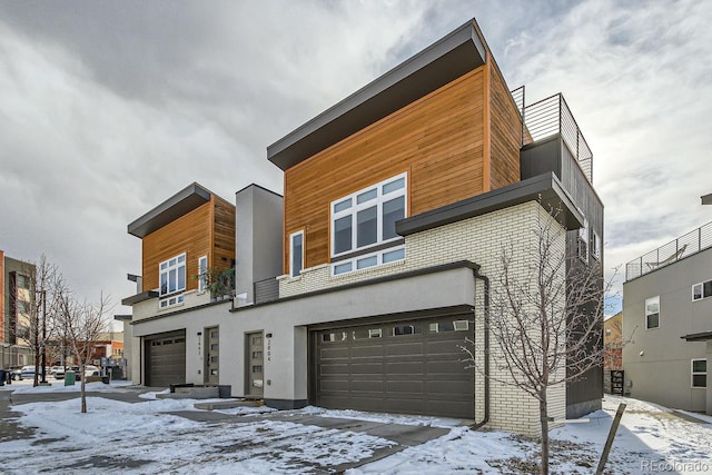 modern home featuring brick siding, a garage, and stucco siding