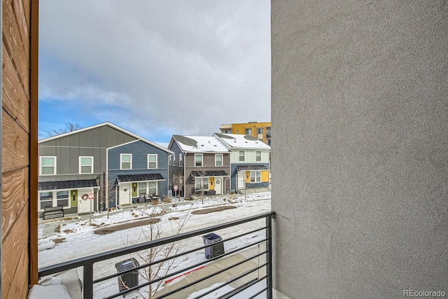 snow covered back of property featuring a residential view