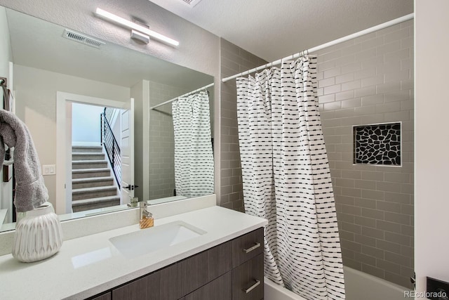 bathroom with vanity, shower / bath combo, visible vents, and a textured ceiling