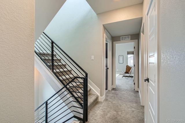 stairs featuring visible vents, carpet floors, baseboards, and a textured wall