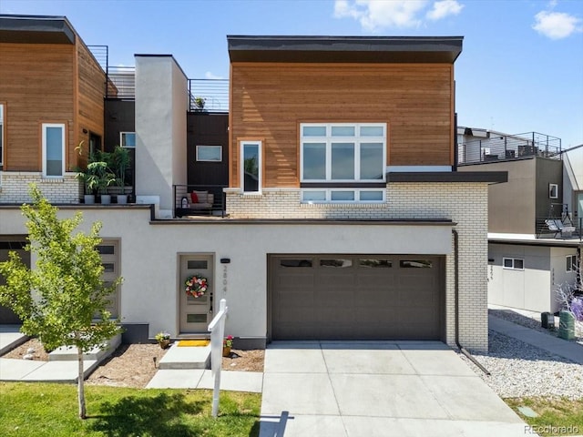 2804 W 53rd Ave, Denver, CO 80221 - contemporary home featuring concrete driveway, a garage, stucco siding, and brick siding