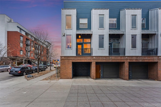 2680 Blake St Unit 12, Denver, CO 80205 - view of front facade featuring an attached garage, brick siding, driveway, and board and batten siding