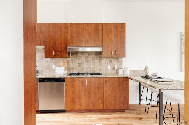 2680 Blake St Unit 12, Denver, CO 80205 - kitchen with appliances with stainless steel finishes, ventilation hood, light wood-type flooring, and light stone countertops