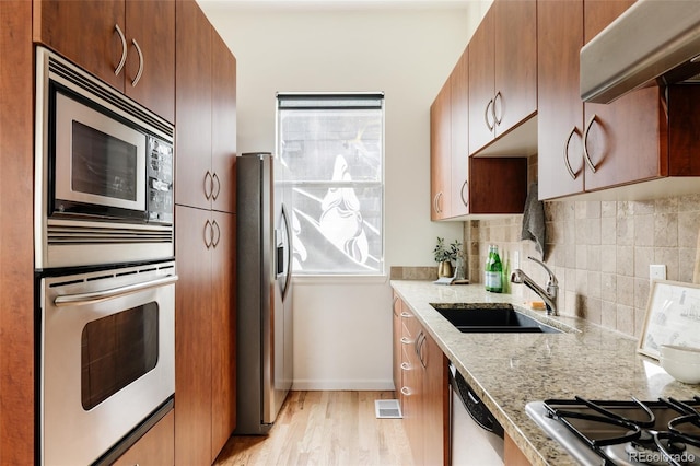 2680 Blake St Unit 12, Denver, CO 80205 - kitchen featuring stainless steel appliances, ventilation hood, light wood-type flooring, a sink, and tasteful backsplash