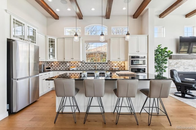 7850 Vallagio Ln, Englewood, CO 80112 - kitchen with appliances with stainless steel finishes, dark countertops, beamed ceiling, tasteful backsplash, and white cabinets
