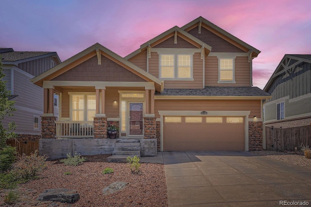 craftsman inspired home featuring an attached garage, driveway, a porch, fence, and stone siding