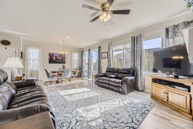 living room with light wood-type flooring, a wealth of natural light, and ceiling fan with notable chandelier