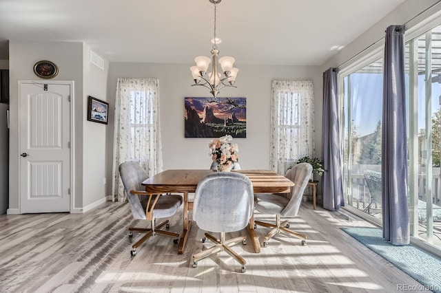 dining space with light hardwood / wood-style floors and a notable chandelier