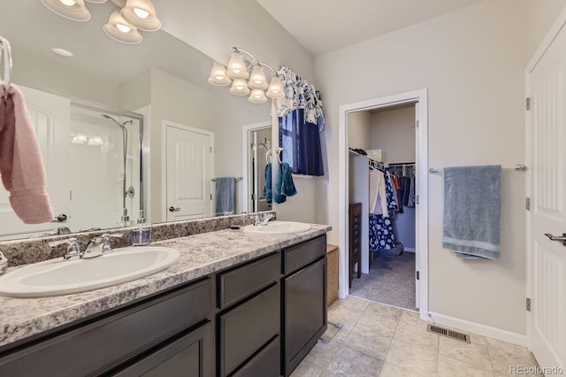 bathroom with a shower with shower door, vanity, and tile patterned flooring