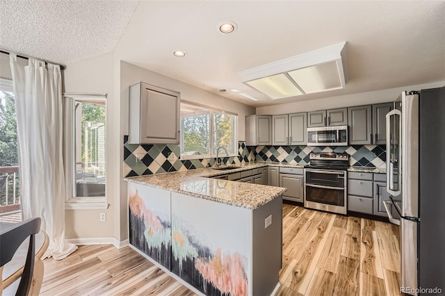 kitchen featuring light hardwood / wood-style floors, stainless steel appliances, sink, and gray cabinets