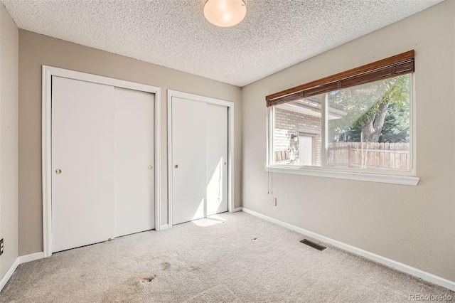 unfurnished bedroom featuring light carpet and a textured ceiling