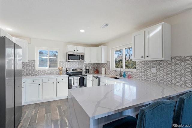 kitchen featuring backsplash, kitchen peninsula, sink, and appliances with stainless steel finishes