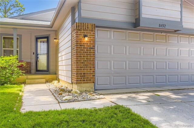 8432 S Upham Way, Littleton, CO 80128 - view of exterior entry with brick siding, a garage, and driveway