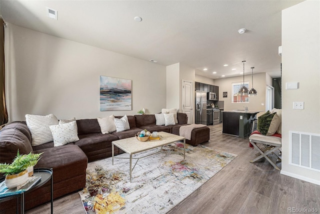 living room featuring light wood-type flooring, baseboards, and recessed lighting