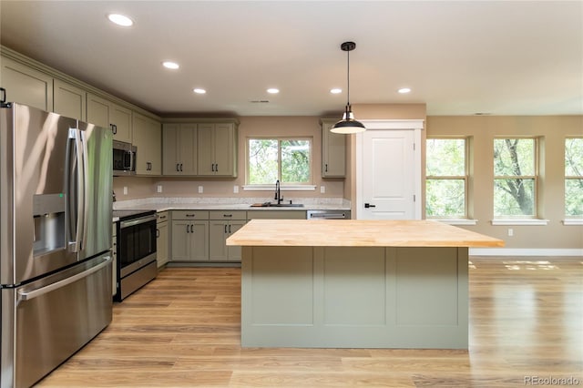 kitchen featuring light wood-type flooring, gray cabinets, butcher block countertops, a center island, and appliances with stainless steel finishes