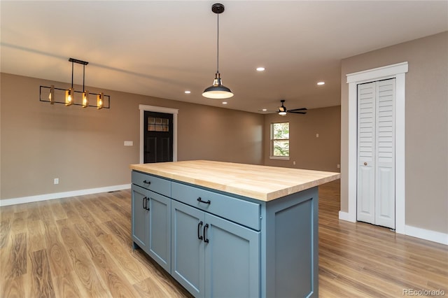 kitchen featuring decorative light fixtures, light hardwood / wood-style flooring, a center island, ceiling fan, and butcher block counters