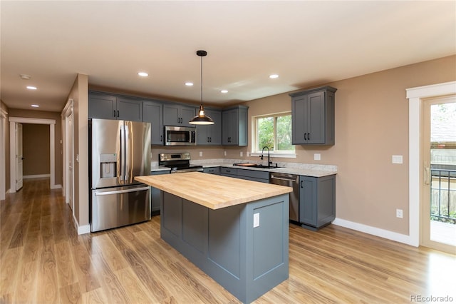 kitchen featuring butcher block countertops, a kitchen island, sink, appliances with stainless steel finishes, and light hardwood / wood-style floors