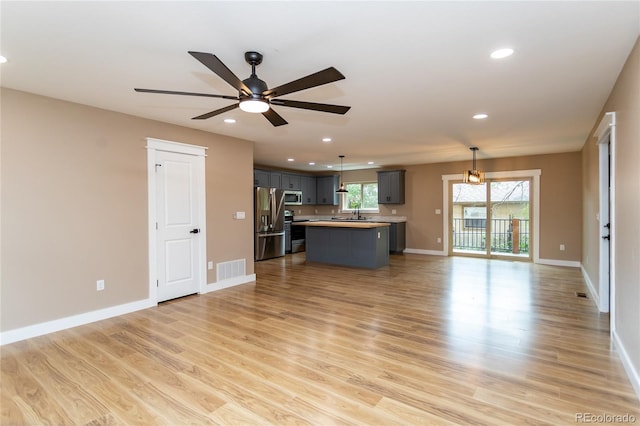 unfurnished living room featuring light wood-type flooring and ceiling fan