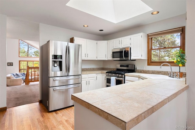 23599 Shingle Creek Rd, Golden, CO 80401 - kitchen with stainless steel appliances, a skylight, white cabinetry, light wood-style flooring, and recessed lighting