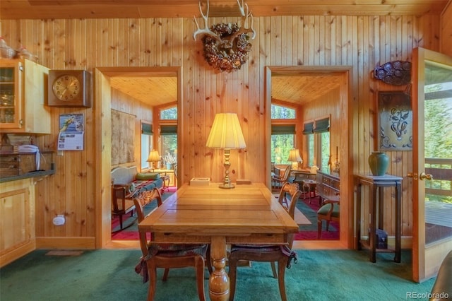 dining room featuring carpet floors, lofted ceiling, and wooden walls