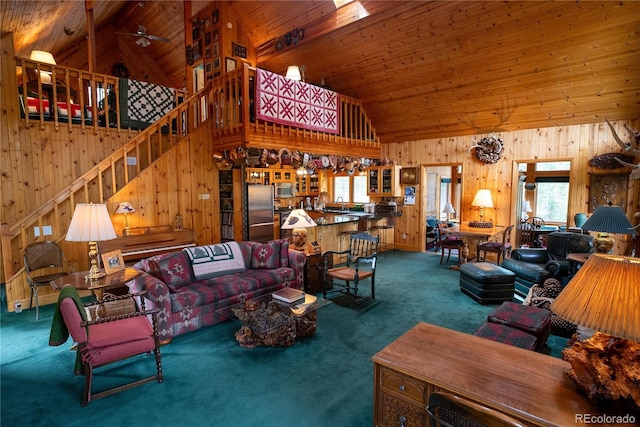 carpeted living room with high vaulted ceiling, wooden ceiling, ceiling fan, and wooden walls