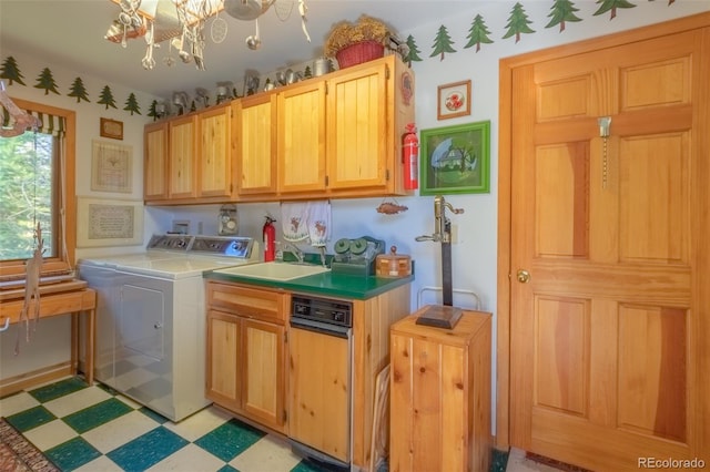 laundry room with sink, cabinets, washing machine and dryer, and a notable chandelier