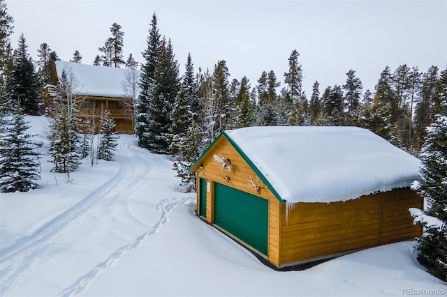 snow covered structure featuring a garage