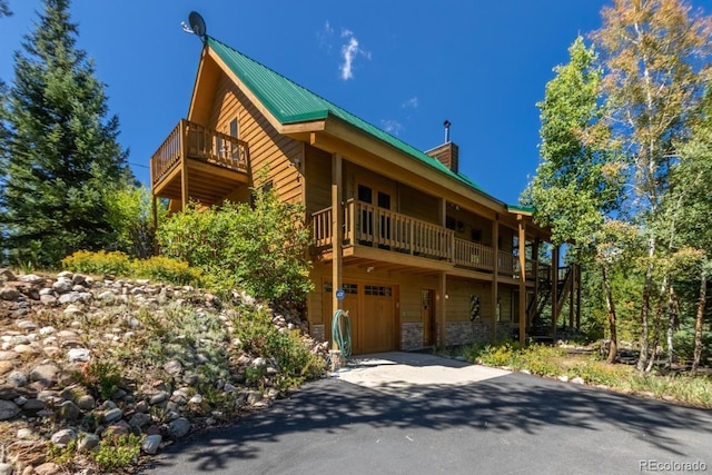 460 Gcr 466, Grand Lake, CO 80447 - view of front of house with a garage, metal roof, stone siding, a chimney, and driveway