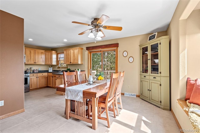 tiled dining room featuring ceiling fan and sink