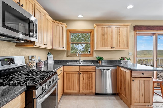 kitchen with a breakfast bar area, light tile patterned floors, sink, kitchen peninsula, and stainless steel appliances