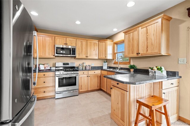 kitchen featuring sink, light brown cabinets, light tile patterned floors, stainless steel appliances, and kitchen peninsula