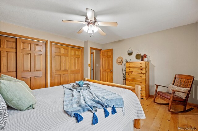 bedroom with light hardwood / wood-style flooring, ceiling fan, and two closets