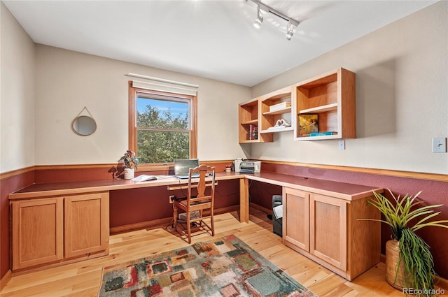 office area with rail lighting, light hardwood / wood-style flooring, and built in desk