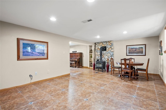 dining space with a wood stove and tile patterned floors