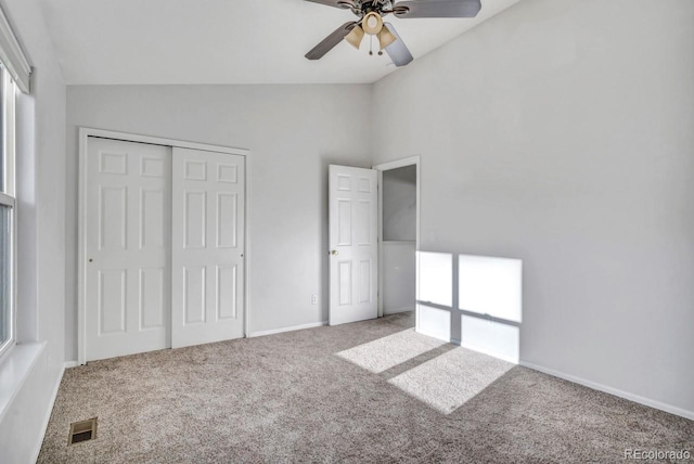 unfurnished bedroom with ceiling fan, a closet, carpet floors, and lofted ceiling