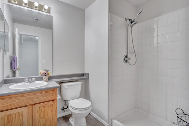 bathroom with vanity, toilet, wood-type flooring, and tiled shower